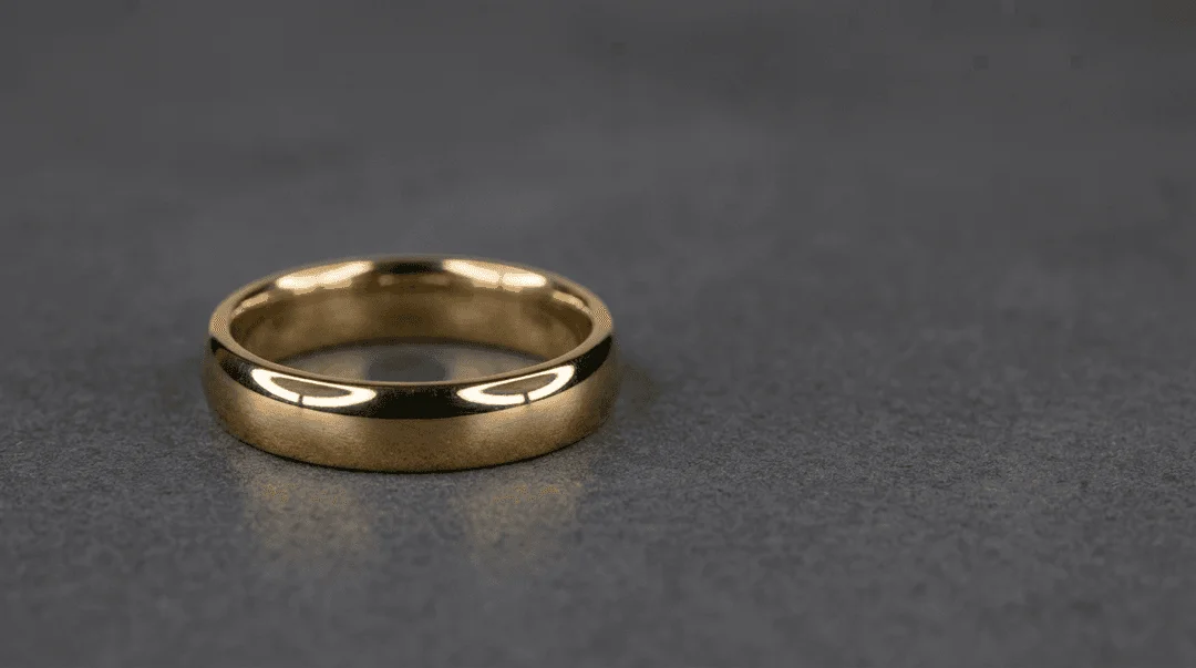 Solitaire gold ring photographed under overhead ring light showing soft metallic highlights