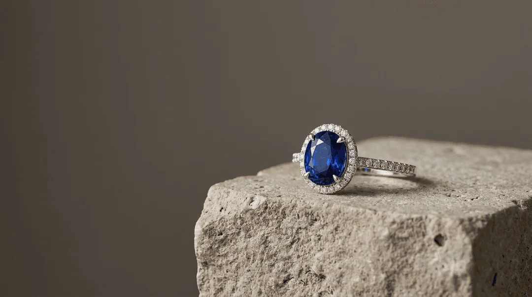 Fine blue sapphire ring resting on limestone pedestal with soft shadows