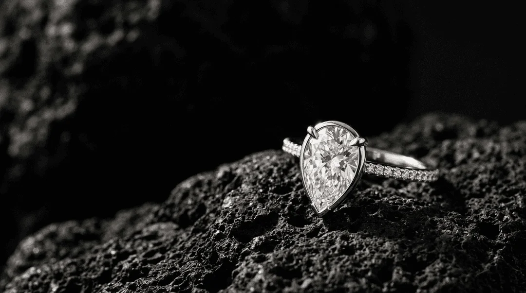 Pear-cut lab-grown diamond ring macro on dark volcanic stone